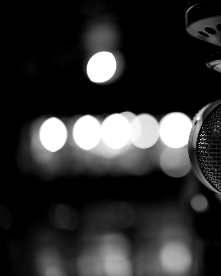 A stage microphone in close-up, stage lights thrown out of focus behind it